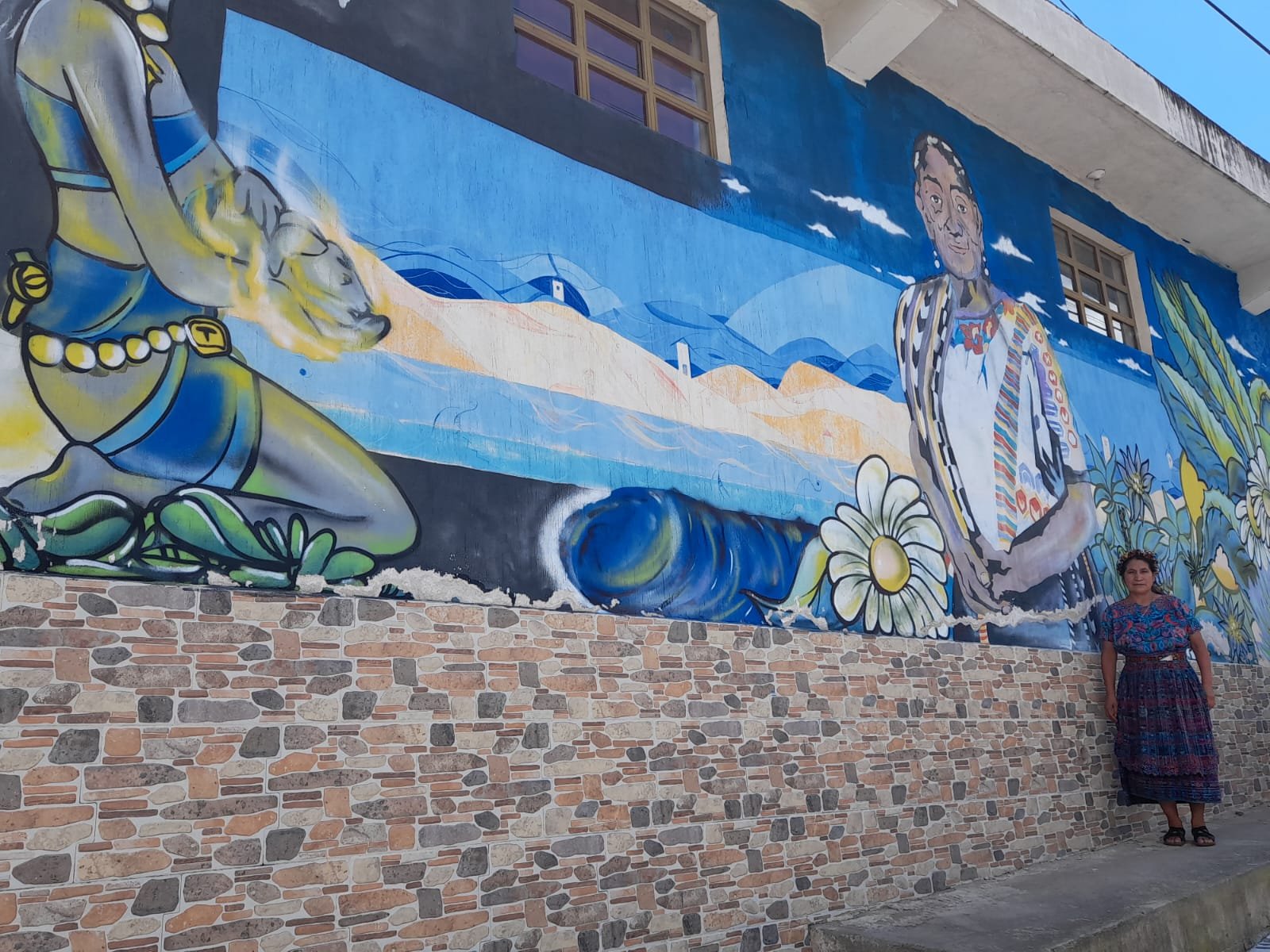  En el mural un dios maya muestra un bebé a una comadrona con indumentaria maya, este está pintado en la sede de la CODECOT. La partera Santos Margarita Lucas explicó que la pintura representa los conocimientos ancestrales y el don sagrado de recibir nuevas vidas.  Foto: Mirna Alvarado 